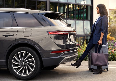 A woman with her hands full uses her foot to activate the available hands-free liftgate.