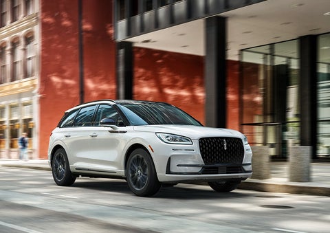 The 2024 Lincoln Corsair® SUV with the Jet Appearance Package and a Pristine White exterior is parked on a city street.