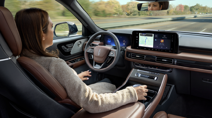 A woman is seen sitting in the driver’s seat of her 2025 Lincoln Aviator® SUV with her hands off the steering wheel. | Asheville Lincoln in Asheville NC