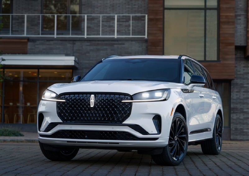 A 2026 Lincoln Aviator® Reserve model is shown with the available Jet Appearance Package parked near a restaurant. | Asheville Lincoln in Asheville NC