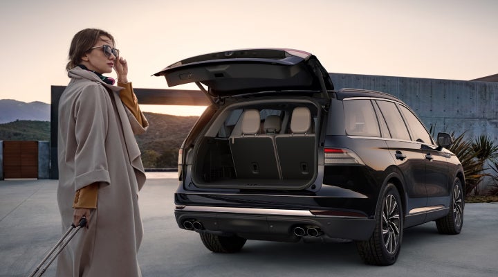 A woman approaches a 2026 Lincoln Aviator® SUV with its rear liftgate open. | Asheville Lincoln in Asheville NC