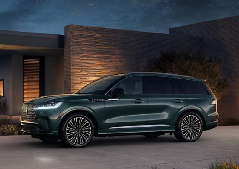 A green 2027 Lincoln Aviator® SUV is parked outside a contemporary home. | Asheville Lincoln in Asheville NC
