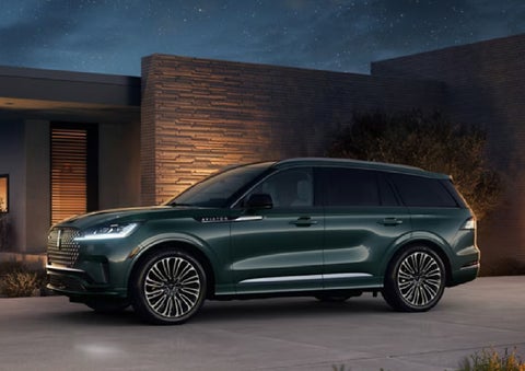 A green 2027 Lincoln Aviator® SUV is parked outside a contemporary home. | Asheville Lincoln in Asheville NC