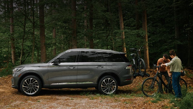 A father and son load e-bikes on a bike rack attached to a 2027 Lincoln Aviator® SUV. | Asheville Lincoln in Asheville NC